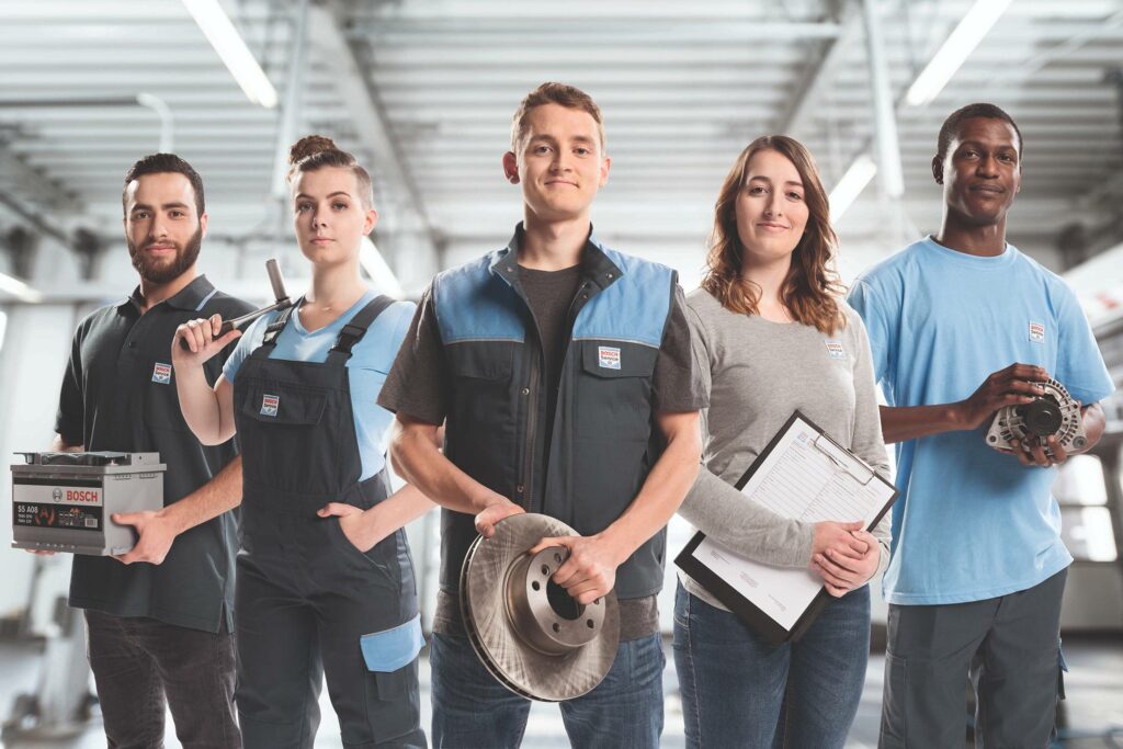 Personal hos Bosch Car Service med bilreservdelar och verktyg i verkstadsmiljö